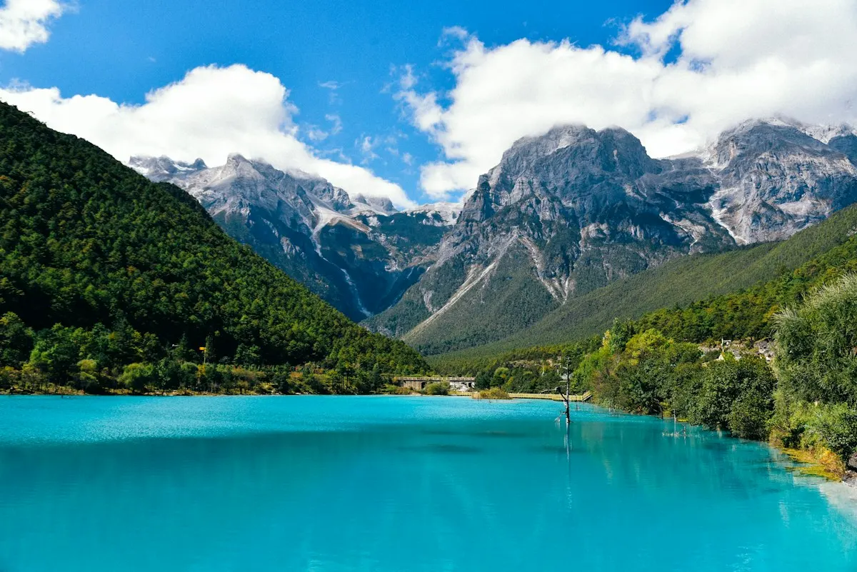 Turquoise water, forested slopes and mountain peaks in Blue Moon Valley, Lijiang, Yunnan.
